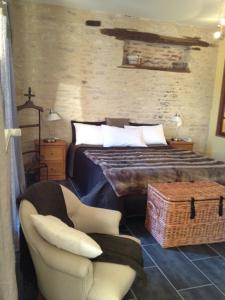a bedroom with a bed and a chair at Logis Hotel La Grange Du Relais in Colombey-les-deux-Églises