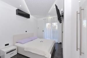 a white bedroom with a bed and a tv at Villa Lily in Privlaka +120 photos