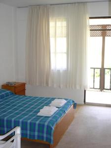 a bedroom with a blue and white bed and a window at Villa Rhapsody Pension in Kayakoy