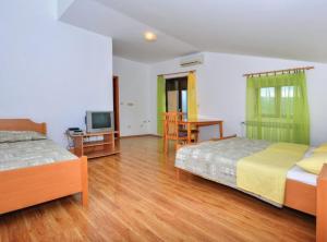 een slaapkamer met 2 bedden, een tafel en een televisie bij Sobe Melada in Trilj