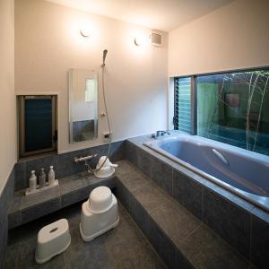 ein Badezimmer mit einer großen Badewanne und zwei Hockern darin in der Unterkunft 唐比ステイ in Isahaya + 31 Fotos