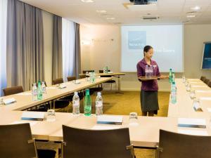 eine Frau, die vor einem Zimmer mit Tischen steht in der Unterkunft Novotel Nice Centre Vieux Nice in Nizza