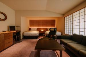 ein Hotelzimmer mit zwei Betten und einer Couch in der Unterkunft Kasan in Kirishima