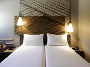 2 weiße Betten in einem Zimmer mit 2 Leuchten in der Unterkunft Hotel ibis Porto Gaia in Vila Nova de Gaia