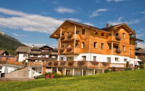 een groot houten huis op een heuvel met bloemen bij Chalet Rudana in Sesto