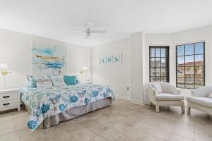 een witte slaapkamer met een bed en een stoel bij Sea Marsh II Stunning Beachfront Stay in Myrtle Beach +9 foto's