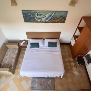 una camera da letto con un letto con lenzuola bianche e un dipinto sul muro di Hotel Casa de Sarah a Santa Marta