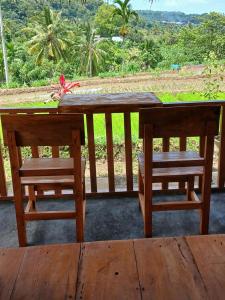 een houten tafel en stoelen met uitzicht op een veld bij meta bungalow in Senaru +3 foto's