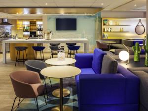 a lobby with a blue couch and tables and a bar at Mercure Rouen Centre Cathédrale in Rouen