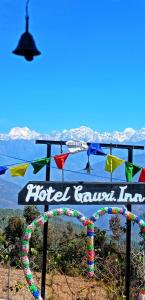 Een uithangbord voor een hotel/ranch/herberg met bergen op de achtergrond. bij Hotel Gauri Inn Charikot in Dolakhā