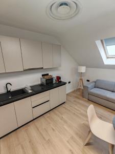 a kitchen with white cabinets and a couch in a room at 44roomsMarghita in Marghita
