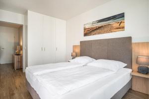 a bedroom with a large bed with white sheets at Seeluft Olpenitz in Olpenitz