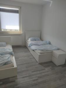 twee bedden in een witte kamer met een raam bij Ganze Wohnung mit privatem Balkon in Gelsenkirchen