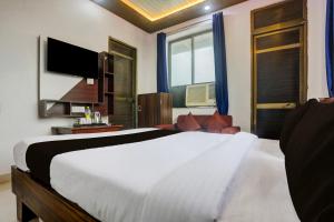 een slaapkamer met een groot wit bed en een televisie bij HOTEL O MJ INN in Darbhanga