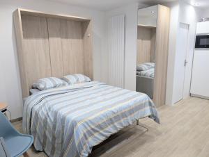 een slaapkamer met een bed met een blauw en wit gestreepte deken bij Studio cosy et équipé proche Paris in Saint-Leu-la-Forêt