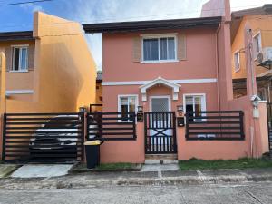 ein rosa-oranges Haus mit einem schwarzen Tor in der Unterkunft Jorich home stay in Dumaguete