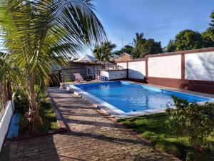 a swimming pool next to a house with a palm tree at MiMi24 in Mahajanga