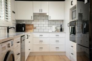 a kitchen with white cabinets and a washer and dryer at Paws & Palms Hideaway in Nelson Bay