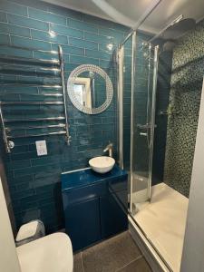 een blauwe badkamer met een wastafel en een douche bij Dancenter Tolcarne Beach hotel in Newquay