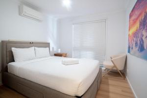 a bedroom with a white bed and a window at Paws & Palms Hideaway in Nelson Bay