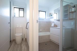 a bathroom with a tub and a toilet and a sink at Paws & Palms Hideaway in Nelson Bay +15 photos