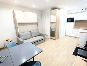 een woonkamer met een bank en een tafel bij Studio cosy et équipé proche Paris in Saint-Leu-la-Forêt