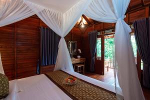 a bedroom with a bed with white drapes at Pondok Naples Ubud in Ubud +22 photos