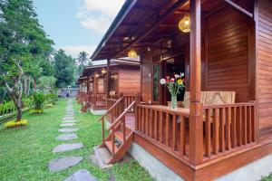 a wooden cabin with a porch with flowers on it at Pondok Naples Ubud in Ubud