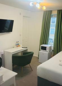 een kamer met een bed, een bureau en een magnetron bij Dancenter Tolcarne Beach hotel in Newquay +1 foto