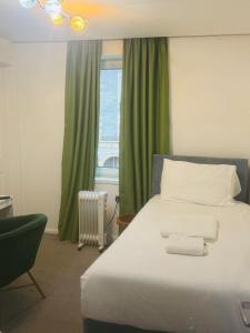 een slaapkamer met een groot bed met groene gordijnen en een raam bij Dancenter Tolcarne Beach hotel in Newquay