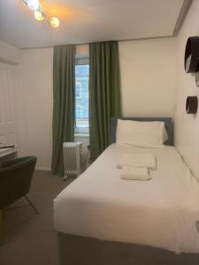 een slaapkamer met een wit bed met een stoel en een raam bij Dancenter Tolcarne Beach hotel in Newquay