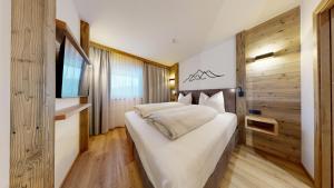 a bedroom with a white bed and a wooden wall at Moonlight Apartments in Söll