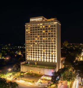 een groot gebouw met 's nachts een bord bij President - IHCL SeleQtions in Mumbai