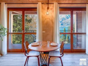a dining room with a table and chairs and windows at THE LOFT by Design Studio in Bellano
