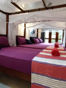 2 bedden in een kamer met paarse en paarse lakens bij Villa Four Seasons in Mirissa