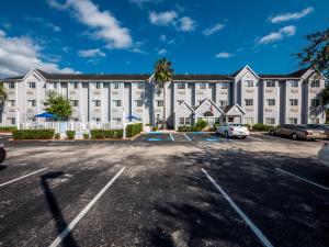 棕櫚海岸的住宿－Microtel Inn & Suites by Wyndham Palm Coast I-95，一座白色的大建筑,汽车停在停车场