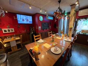 a dining room with a wooden table and red walls at Hitsujipotchi-Kyoto in Yatsuai