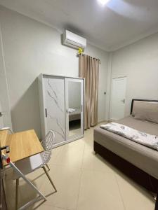 a bedroom with a bed and a table and a chair at Utama Guest House Kuta Alam in Banda Aceh