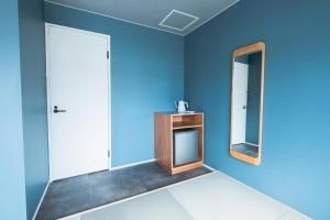 een blauwe badkamer met een spiegel en een houten tafel bij B Cycleトリプルルーム in Biei +26 foto's