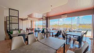 een restaurant met tafels en stoelen en een groot raam bij Azana Style Hotel Jombang in Peterongan