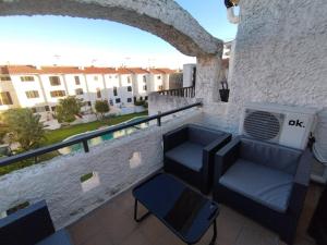 un balcone con divano e sedia su un edificio di Acogedor adosado con piscina a Torredembarra