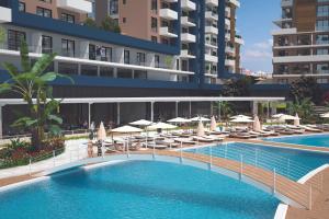 a swimming pool with chairs and umbrellas in front of a building at Rıversıdelıfe Iskele M 147 in Aglantzia