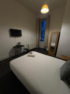 una camera da letto con un grande letto bianco e una televisione di Piccolo Guest House a Glasgow