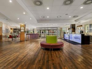 汉堡汉堡沃尔克斯公园美居酒店 的空荡荡的大厅里摆着一张绿色的桌子和一张沙发。