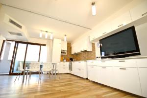 a kitchen with white cabinets and a large flat screen tv at Royal Sea House in Cefalù