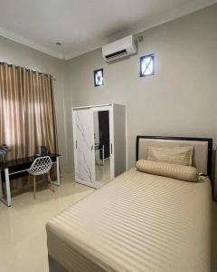 a bedroom with a bed and a desk and a window at Utama Guest House Kuta Alam in Banda Aceh +6 photos