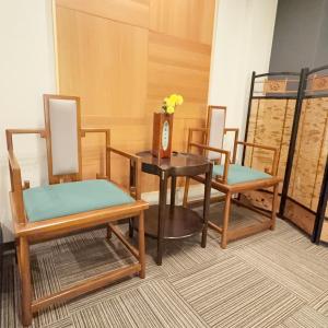 een kamer met drie stoelen en een tafel met een vaas met bloemen bij 大同ガーデンホテル京都 in Kyoto