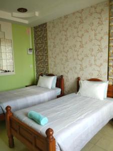 two beds in a room with green walls at บ้านพักสายรุ้ง เพรชรบุรี in Tha Chang