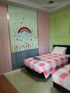 two beds in a room with a rainbow on the wall at บ้านพักสายรุ้ง เพรชรบุรี in Tha Chang