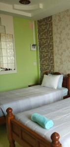 two twin beds in a room with green walls at บ้านพักสายรุ้ง เพรชรบุรี in Tha Chang